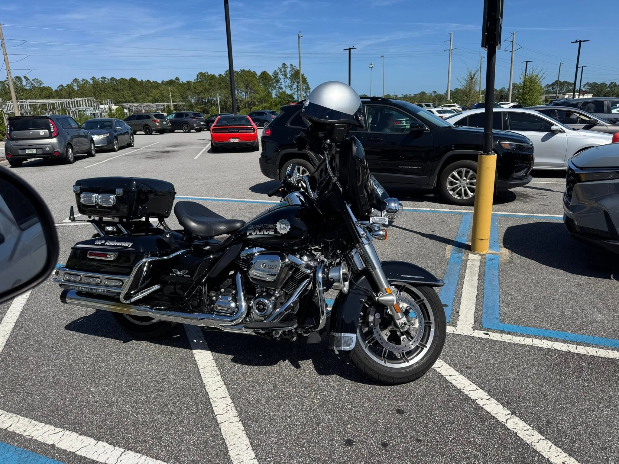 A motorcycle parked across the striped access aisle next to an accessible parking space